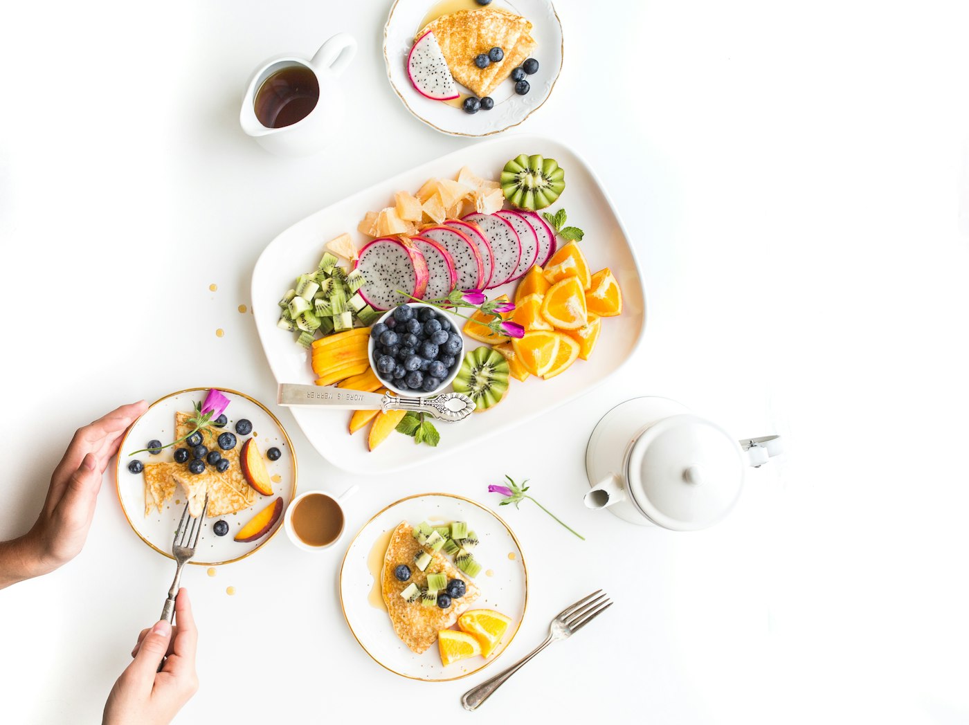 A shared breakfast of fruit, pancakes, and tea